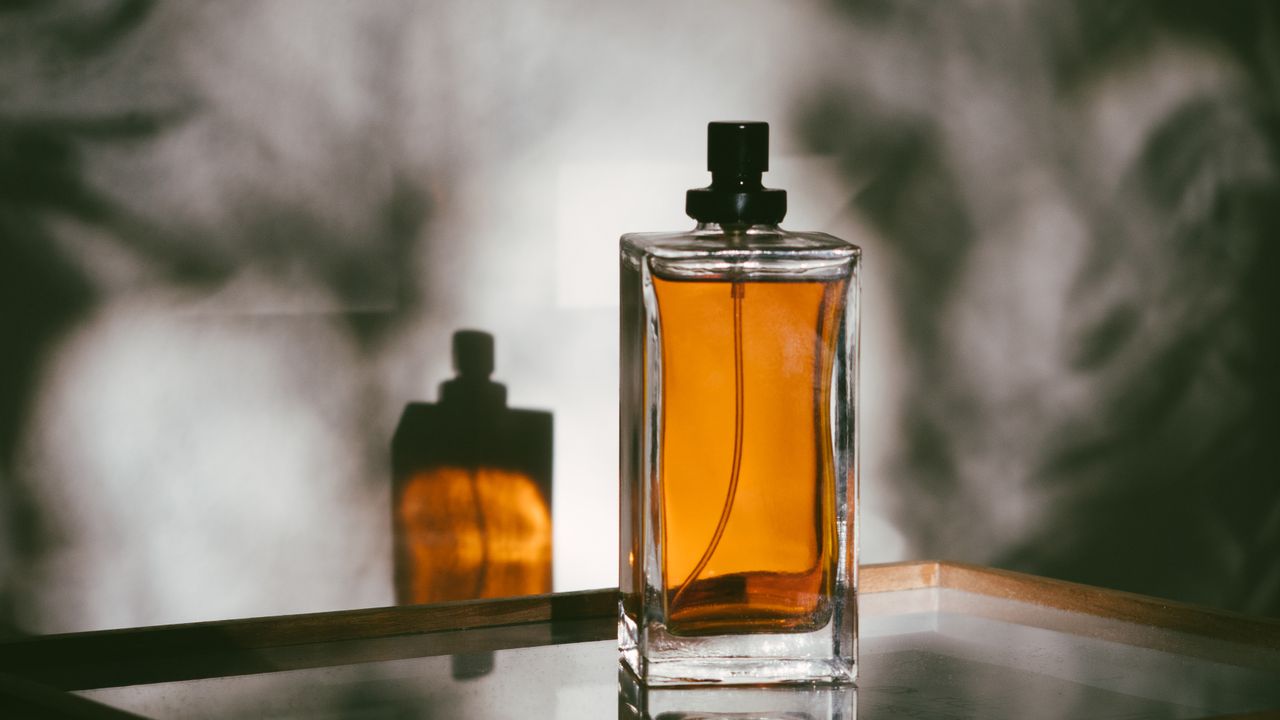 Two amber glass bottles on a mirrored surface, soft smoke drifting behind them